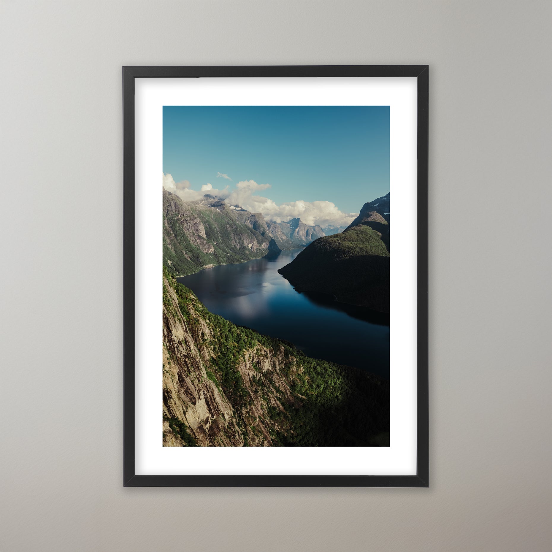 Dramatisk utsikt över en djupblå fjord i Norge, omgiven av höga, grönskogade berg och klippväggar under en delvis molnig himmel i olika storlekar: 30x40 cm, 40x50 cm, 50x70-cm, 70x100 cm.